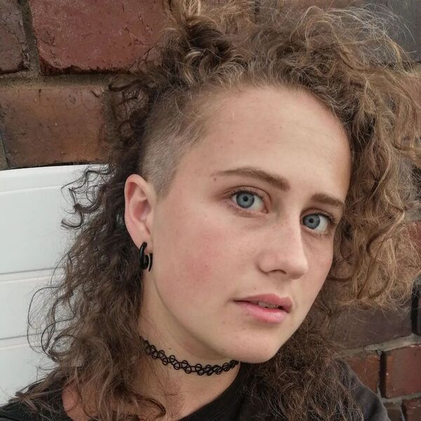 Curly Mullet with Side Shaved Undercut- a woman wearing a black t-shirt