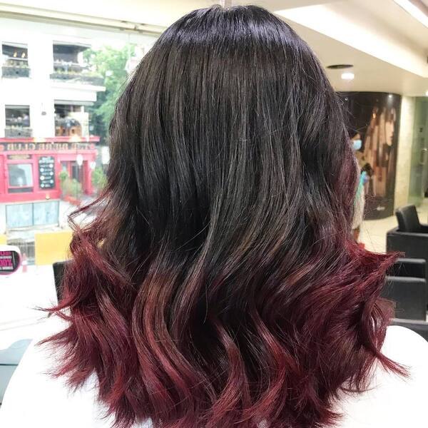 Dark Hair with Red Ombre- a woman wearing a white barber's cape