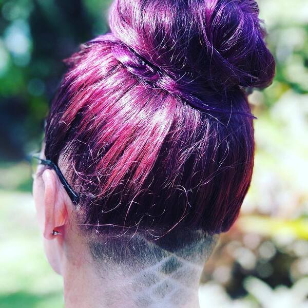 Faded Nape Undercut Design with Purple Hair Bun- a woman wearing an earring
