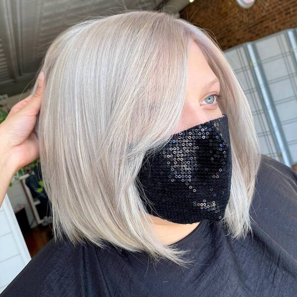 Full Platinum Blonde Blunt Bob- a woman wearing a black face mask and a black barber's cape