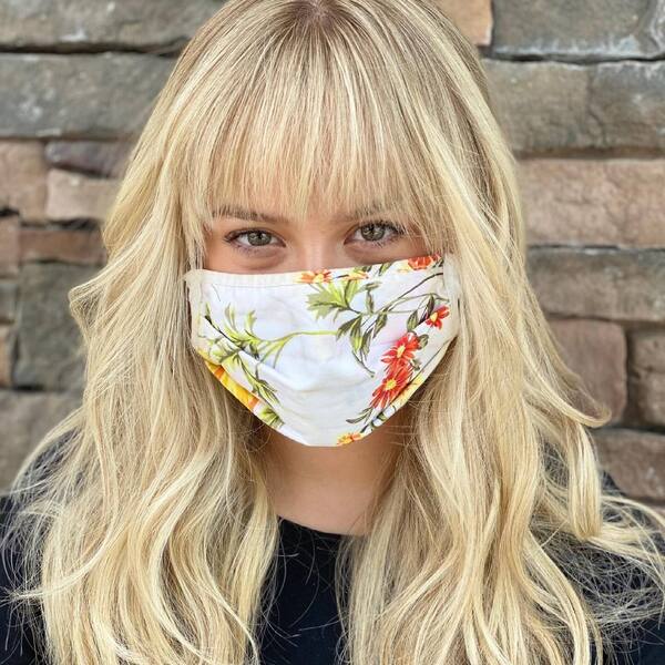 Long Blonde Shag with Bangs- a woman wearing a white face mask