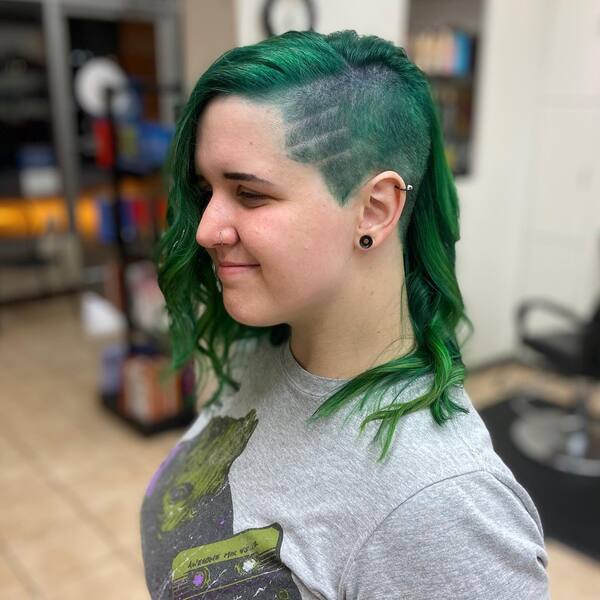 Side Undercut Design with Edgy Green Wavy Hair- a woman wearing a gray t-shirt