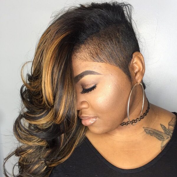 Side Undercut with Long Textured Hair and Caramel Highlights- a woman wearing a big earring