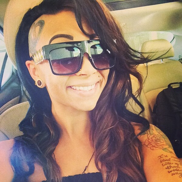 Side Undercut with Long Wavy Hair and Tattoo- a woman wearing a sun glass