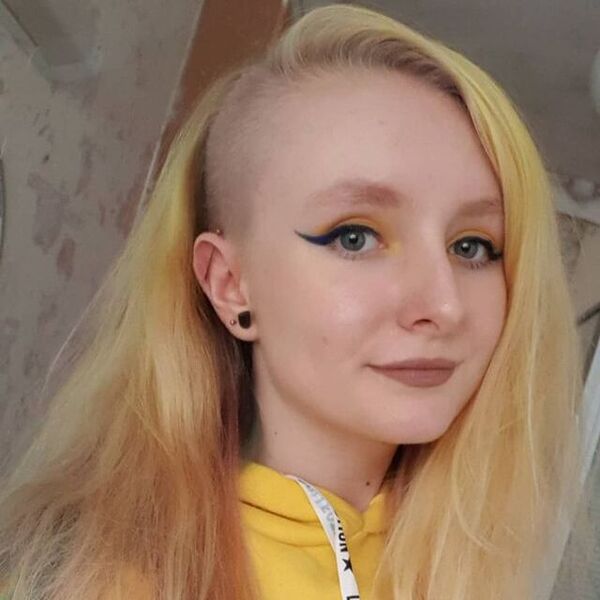 Simple Deep Side Undercut with Blonde Straight Hair- a woman wearing a yellow jacket