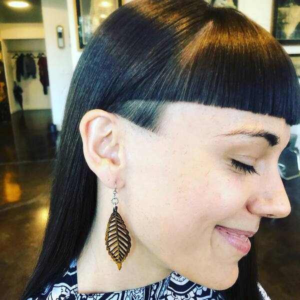 Subtle Side Undercut with Straight Hair and Fringe- a woman wearing a large earring