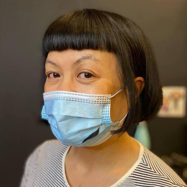 Baby Bangs Short Hairstyles- a woman wearing a face mask