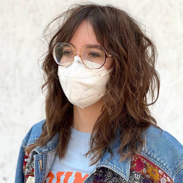 Classic Shag Haircut- a woman wearing a white face mask and a denim jacket