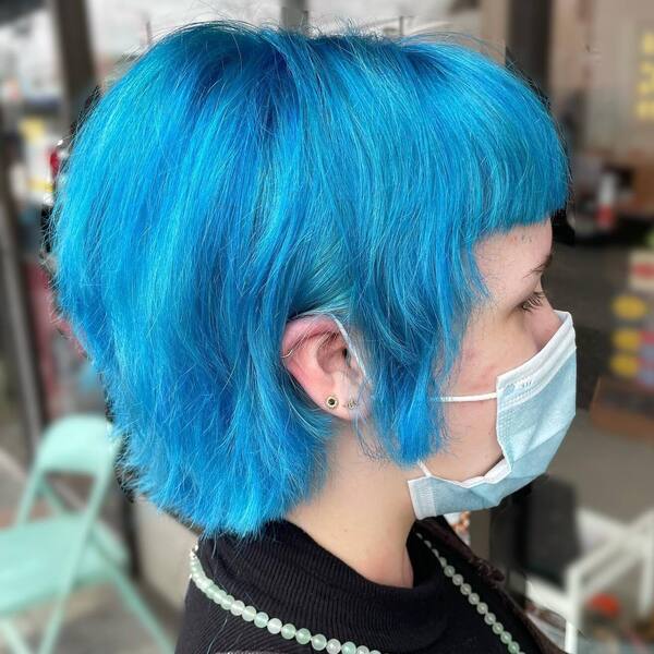 Clear Dreamy Blue Hair Color Ideas- a woman wearing a face mask and a black dress