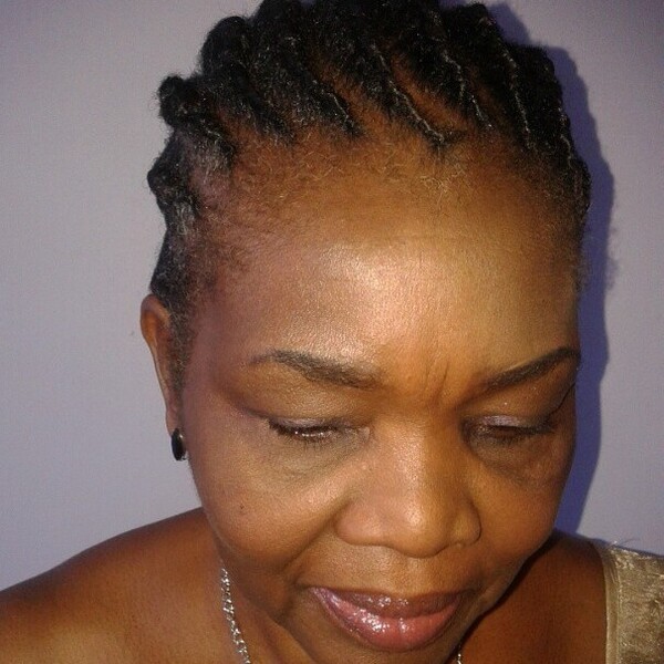 Cornrows- a woman over 60 wearing a silver necklace