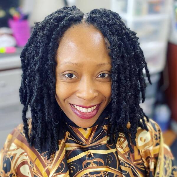 Crochet Braids- a black woman wearing a barber's cape