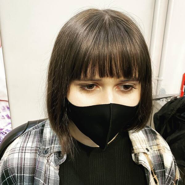 Cute and Edgy Bob Cut with Bangs- a woman wearing a black face mask