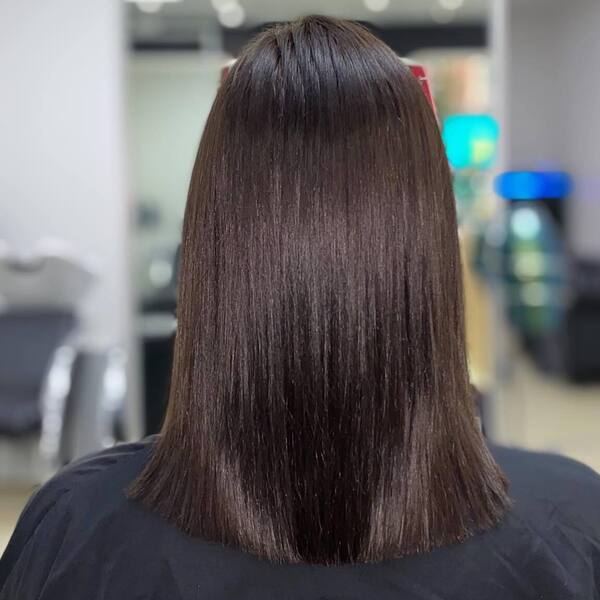 Dark Chestnut Hair Colors- a woman wearing a black barber's cape