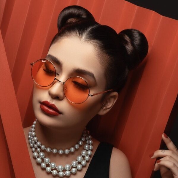 Double Buns- a woman wearing a shades and a white necklace
