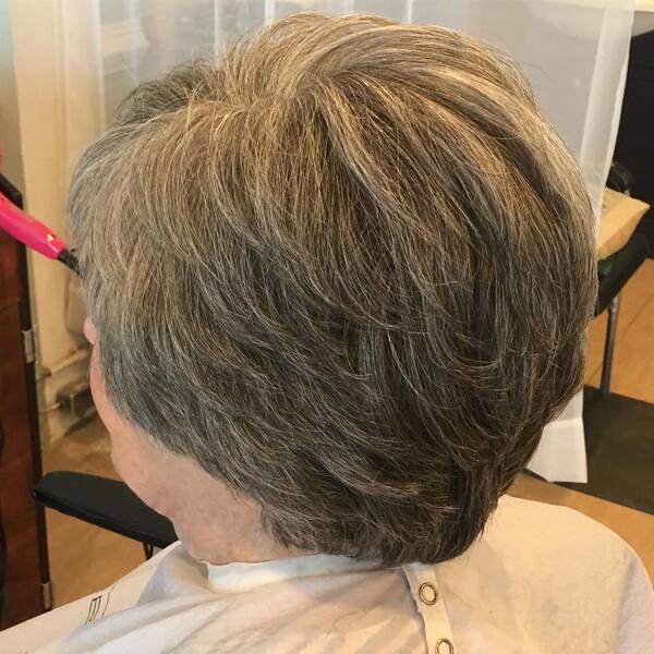Feathered Short Hair- a woman over 60 wearing a barber's cape