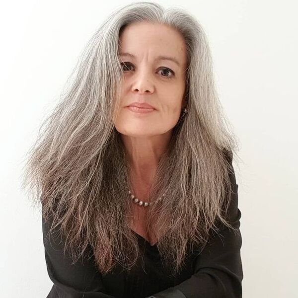 Flowing Hairstyle for Women with Natural Gray Hair- a woman with gray hair wearing a black suit