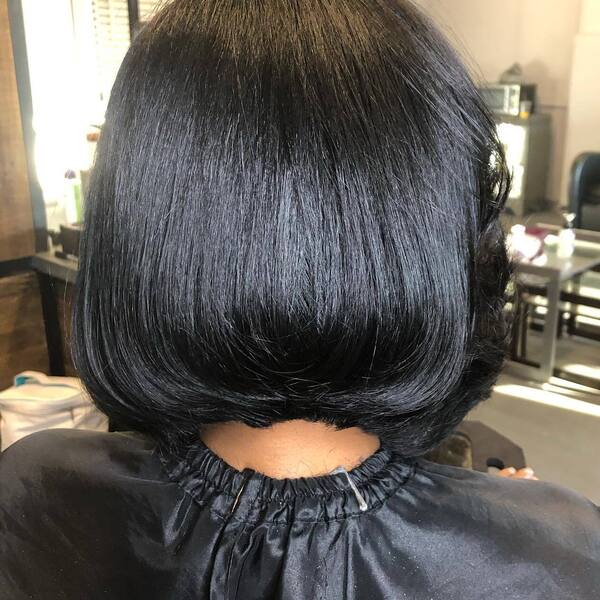 Freshly Silk-Pressed Hairstyle- a black woman wearing a black barber's cape