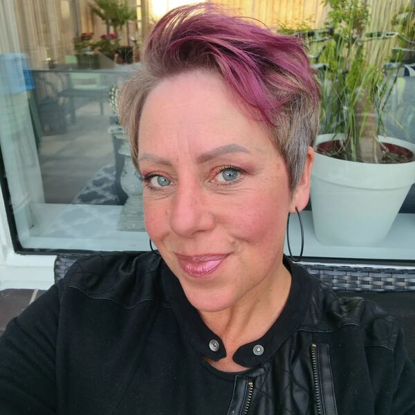 Gray Hair with Purple Top Hair Color- a woman with gray hair wearing a black jacket