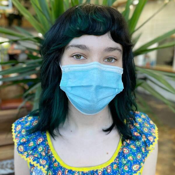 Green Undertones Hairstyles- a woman wearing a light blue face mask