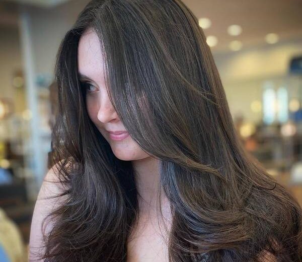 Long Layered Blow-out Brunette Hair- a woman wearing a black camisole
