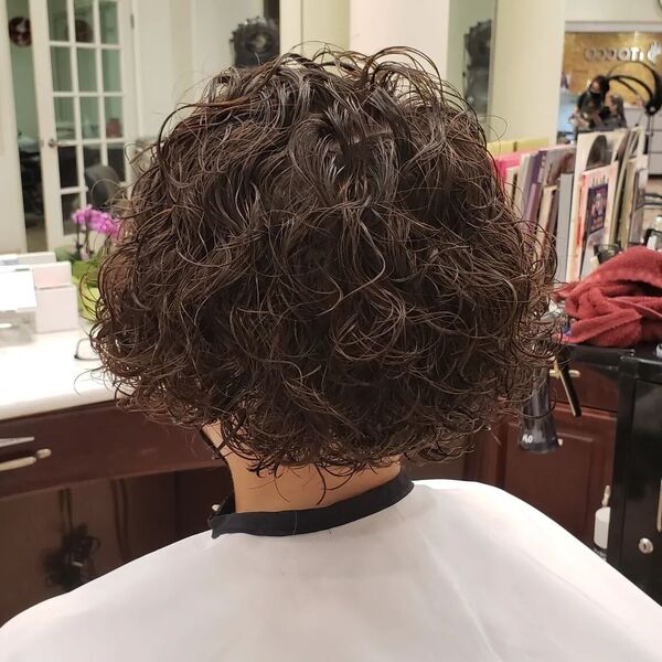 Messy Curly Bob- a woman wearing a white barber's cape