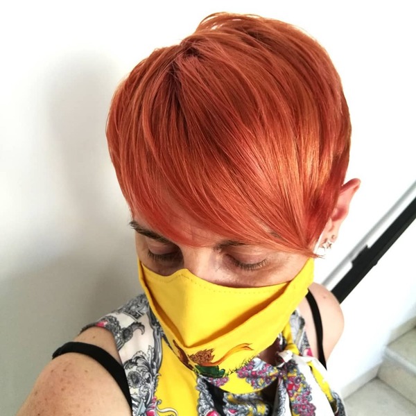 Orange Hair Pixie Cut- a woman wearing a yellow face mask