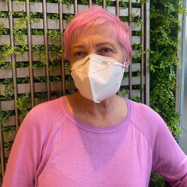 Pixie Cut with Pink Hair Color- a woman wearing a face mask and a pink sweater