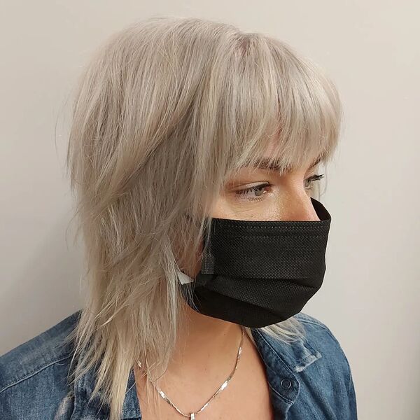 Platinum Blonde Shag Haircut- a woman wearing a black face mask and a denim jacket