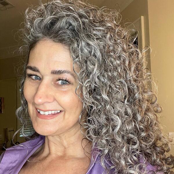 Puffy Curls for Growing out Gray Hair- a woman with gray hair wearing a purple blouse
