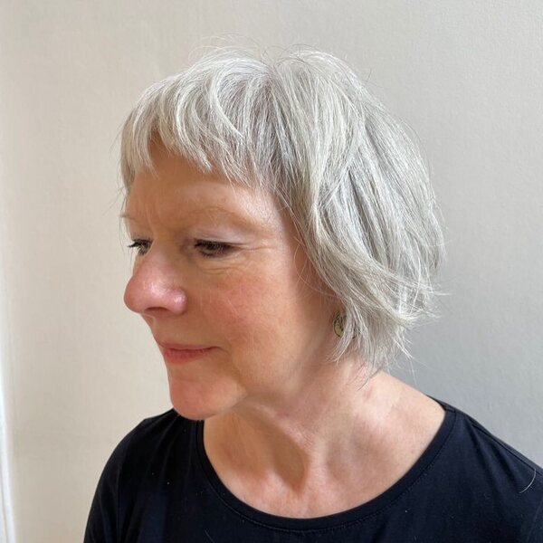 Short Fringe Hair with Bangs- a woman over 60 wearing a black shirt