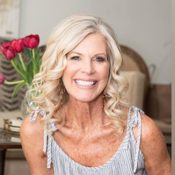 The Natural White Long Hairstyle for Curly Hair- a woman over 60 wearing a gray camisole