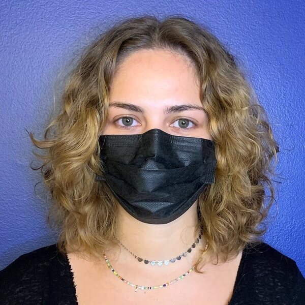 Curly Medium Hairstyles - a woman wearing a black face mask