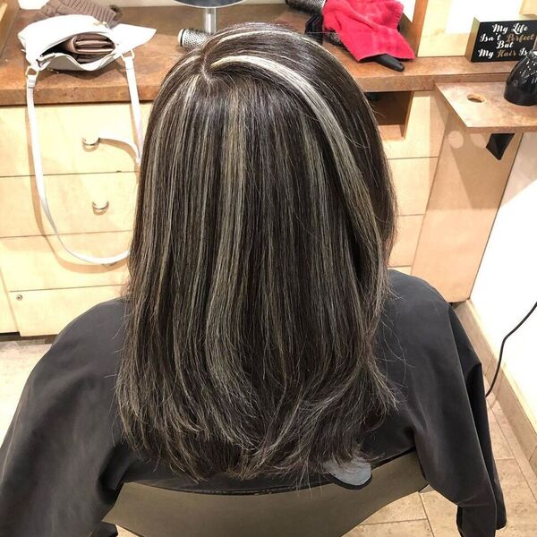 Gray Hair Color Highlights- a woman wearing a black barber's cape