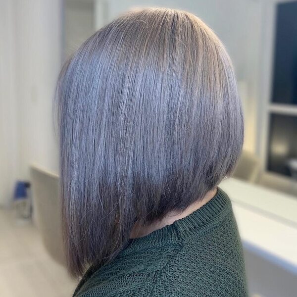 Sharp A-line Gray Hair Color- a woman wearing an olive green sweater